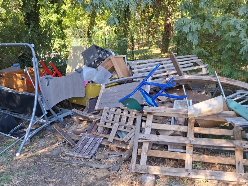 Cadre de lit, caissons en bois, tabouret rouge et meubles empilés en attente d'évacuation