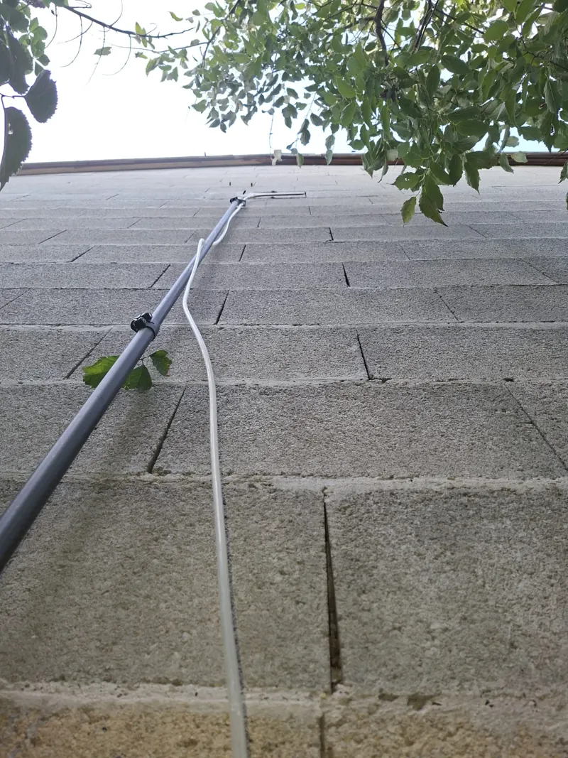 Perche télescopique déployée vers un nid de frelons le long d'une façade