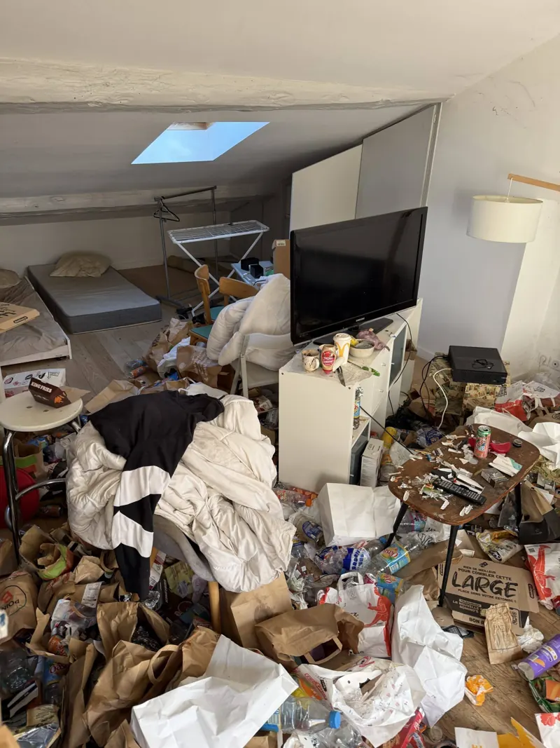 Pièce d'un logement squatté encombrée de déchets avant intervention